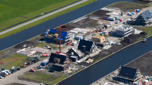 Lemmer Netherlands 21 April 2026 Aerial view of a residential construction site with houses under development a red crane and construction vehicles situated between canals. Lemmer Netherlands 21 April 2026 Aerial view of a residential construction site with houses under development a red crane and construction vehicles situated between canals.