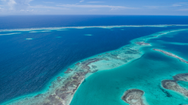 Aerial view of Los Roques archipelago featuring vibrant turquoise waters coral reefs and shallow sandbanks under a clear blue sky in Los Roques Dependencias Federales Venezuela. Aerial view of Los Roques archipelago featuring vibrant turquoise waters coral reefs and shallow sandbanks under a clear blue sky in Los Roques Dependencias Federales Venezuela.