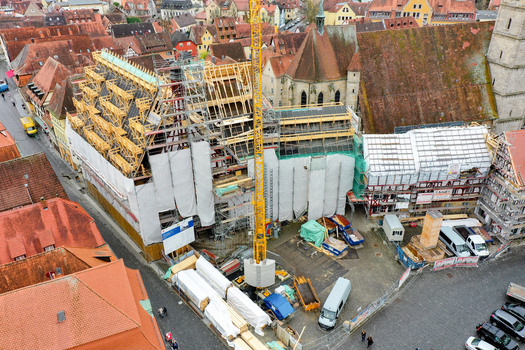 Aerial view of the Rathaus Forchheim under renovation with scaffolding and a crane surrounded by historic red tiled rooftops and people in Forchheim Bayern Germany. Aerial view of the Rathaus Forchheim under renovation with scaffolding and a crane surrounded by historic red tiled rooftops and people in Forchheim Bayern Germany.