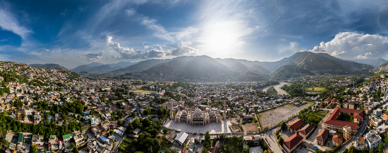 Aerial view of the grand mosque surrounded by dense urban housing a winding river and distant mountains in Muzaffarabad Azad Kashmir Pakistan. Aerial view of the grand mosque surrounded by dense urban housing a winding river and distant mountains in Muzaffarabad Azad Kashmir Pakistan.