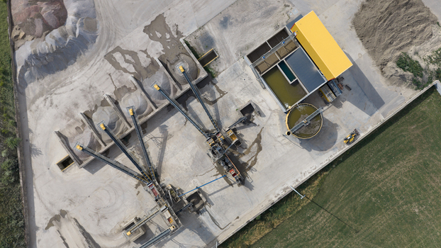 Aerial view of a gravel and sand processing plant with conveyor belts storage piles and industrial machinery in an open industrial site in La Longueville Hauts de France France.