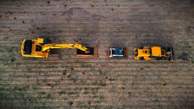 Aerial view of heavy construction machinery including an excavator a skid steer and a loader parked in a row on a tilled agricultural field in Loma Colorado United States. Aerial view of heavy construction machinery including an excavator a skid steer and a loader parked in a row on a tilled agricultural field in Loma Colorado United States.