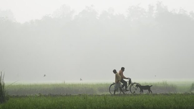 View of a man walking with a bicycle in thick morning fog Bangladesh.