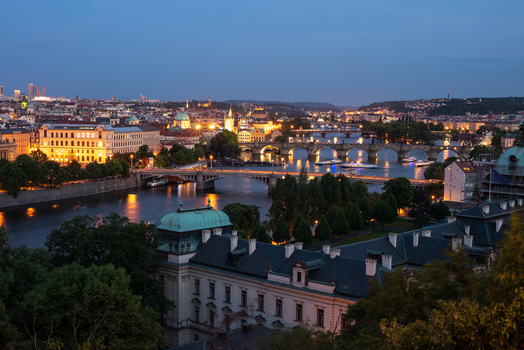 View of the Vltava River and Charles Bridge at twilight with historic buildings and illuminated rooftops in Prague Prague Czechia.