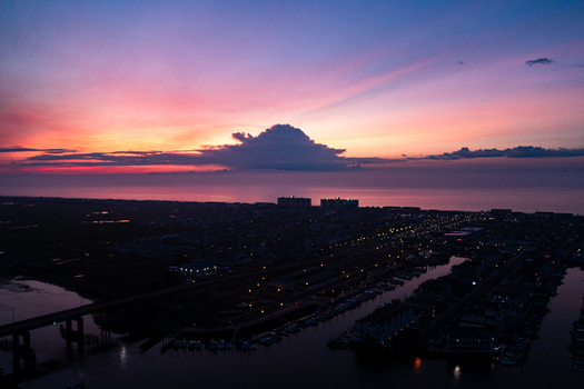Aerial view of Sea Isle City Beach at sunset with vibrant pink and orange sky over the Atlantic Ocean coastal town lights and marina in Sea Isle City New Jersey United States.