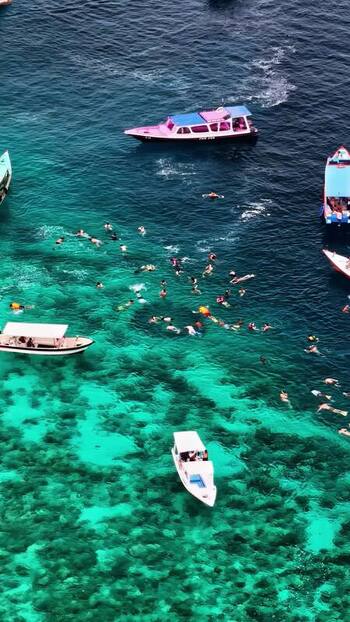 Aerial view of boats and swimmers in turquoise water Indonesia.