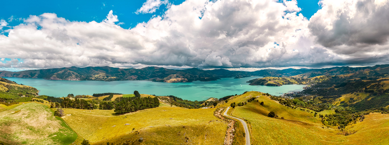 Aerial view of the scenic Akaroa harbour surrounded by rolling green hills winding roads and turquoise waters in Akaroa Canterbury Region New Zealand. Aerial view of the scenic Akaroa harbour surrounded by rolling green hills winding roads and turquoise waters in Akaroa Canterbury Region New Zealand.