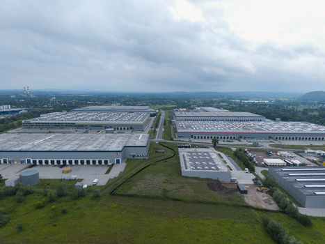 Aerial view of a large logistics hub featuring expansive warehouse buildings with loading docks surrounded by green fields under a cloudy sky in Skawina Lesser Poland Voivode Poland. Aerial view of a large logistics hub featuring expansive warehouse buildings with loading docks surrounded by green fields under a cloudy sky in Skawina Lesser Poland Voivode Poland.