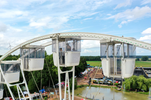 Herzogenaurach Germany 27 July 2025 Aerial view of Open Beatz Festival featuring a white Ferris wheel with people in gondolas overlooking festival grounds and green fields. Herzogenaurach Germany 27 July 2025 Aerial view of Open Beatz Festival featuring a white Ferris wheel with people in gondolas overlooking festival grounds and green fields.