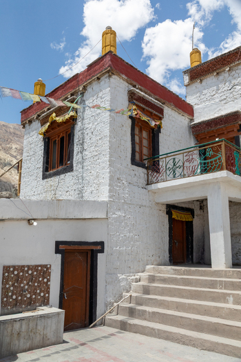 View of the traditional white washed walls and red trim of Charasa Gonpa with prayer flags and stone steps in Charasa Ladakh India.