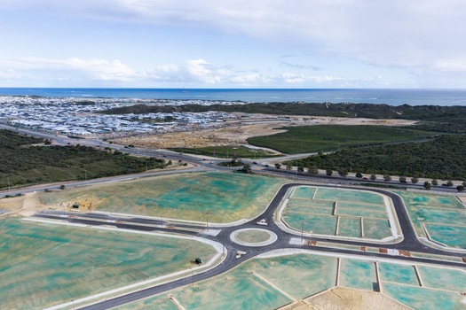 Aerial view of a new residential development site with a newly paved roundabout road network and green erosion control netting near the coast in Perth Western Australia Australia. Aerial view of a new residential development site with a newly paved roundabout road network and green erosion control netting near the coast in Perth Western Australia Australia.