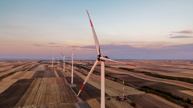 Aerial view of a damaged wind turbine with charred blades standing in a vast agricultural field at sunset in Vladimirovac Vojvodina Serbia.