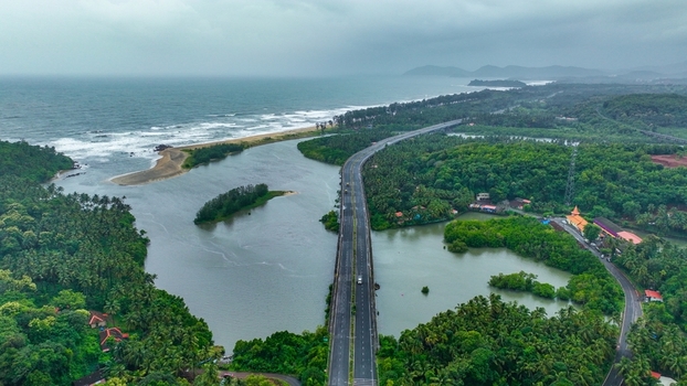 Aerial view of Galgibaga Beach featuring a bridge spanning the river estuary surrounded by dense tropical greenery and the coastline in Canacona Goa India.