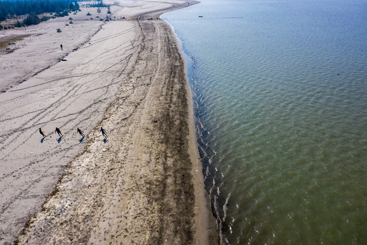 Aerial view of Kuakata beach with people walking along the sandy shoreline and the calm sea in Kuakata Barisal Division Bangladesh. Aerial view of Kuakata beach with people walking along the sandy shoreline and the calm sea in Kuakata Barisal Division Bangladesh.