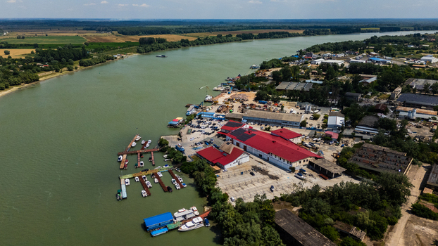 Aerial view of the riverfront in Tulcea featuring a marina with docked boats industrial buildings with red roofs and surrounding green landscape in Tulcea Tulcea Romania.