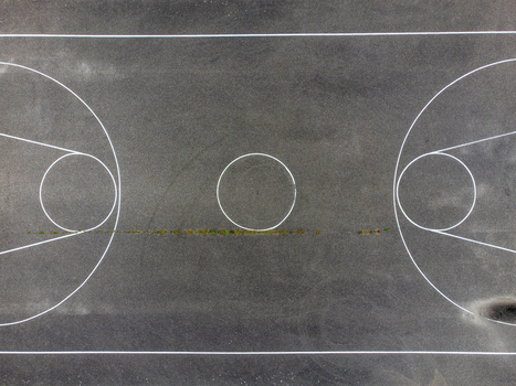 Aerial view of a weathered basketball court marked with white lines and a touch of green moss Radiopad Flevoland Netherlands.