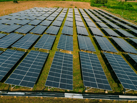 Aerial view of a large solar farm with rows of photovoltaic panels installed on a grassy field in Ogun State Nigeria.