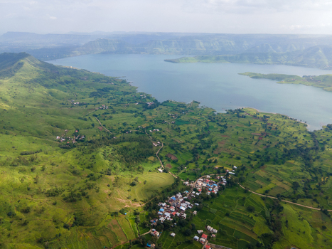 Aerial view of Kaas plateau with lush green hills a large lake and a small village nestled in the landscape in Satara Maharashtra India.