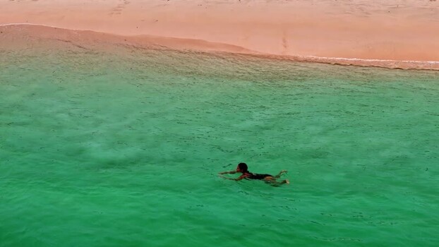 Aerial view of woman swimming in turquoise water Indonesia.