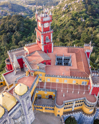 Aerial view of Pena Castle clock tower with forest in background view of the Romanticist castle on hilltop Sintra Lisbon Portugal.