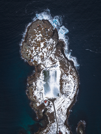 Aerial view of a rugged coastline kissed by snow and embraced by the deep blue sea Henningsv&aelig;r Nordland Norway.