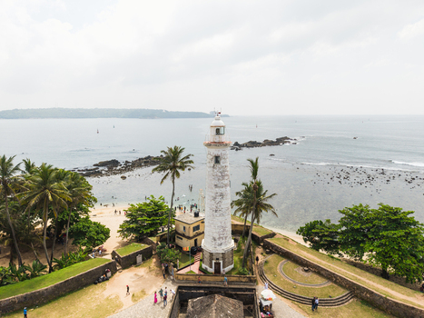 Aerial view of Galle Lighthouse standing on the historic fort walls with palm trees and the Indian Ocean in the background Galle Southern Province Sri Lanka. Aerial view of Galle Lighthouse standing on the historic fort walls with palm trees and the Indian Ocean in the background Galle Southern Province Sri Lanka.