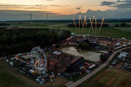 Herzogenaurach Germany 27 July 2025 Aerial view of the Open Beatz Festival featuring a large ferris wheel vibrant stages and fireworks displays over a crowd of people at sunset. Herzogenaurach Germany 27 July 2025 Aerial view of the Open Beatz Festival featuring a large ferris wheel vibrant stages and fireworks displays over a crowd of people at sunset.