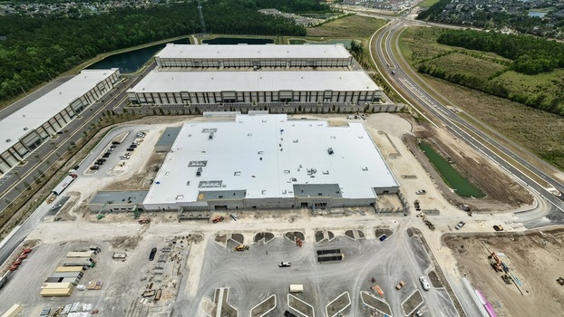 Aerial view of large industrial warehouses and construction site at Foundry Lane with white rooftops and surrounding greenery World Golf Village Florida United States.