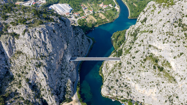 Aerial view of the Cetina River canyon bridge spanning between steep limestone cliffs and turquoise water in Omis Split Dalmatia County Croatia. Aerial view of the Cetina River canyon bridge spanning between steep limestone cliffs and turquoise water in Omis Split Dalmatia County Croatia.