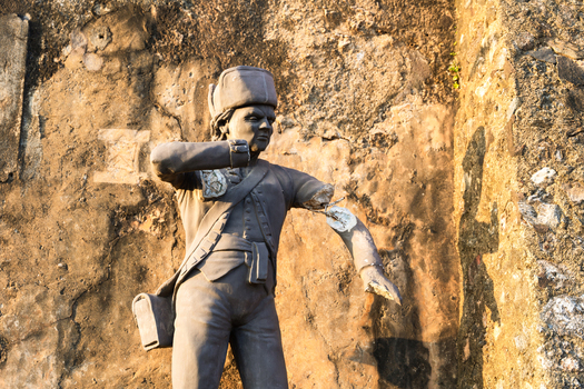 View of a weathered statue of a colonial soldier with a broken arm against an ancient stone wall in Galle Southern Province Sri Lanka.