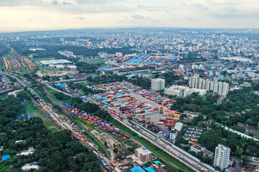Aerial view of Chattogram Port featuring rows of colorful shipping containers industrial cranes and railway tracks amidst the urban landscape of Chittagong Chittagong Division Bangladesh.
