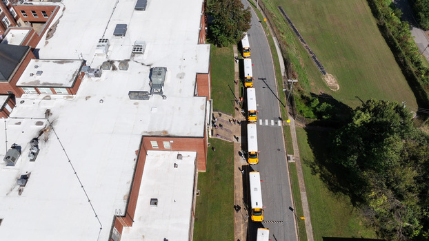 Aerial view of a school building with a line of yellow school buses parked along the road in Lynchburg Virginia United States.