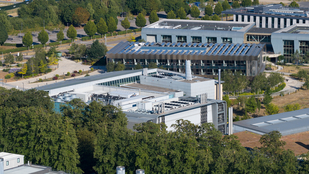 Aerial view of the Wellcome Genome Campus featuring modern research buildings with solar panels surrounded by lush trees and green landscapes in Hinxton England United Kingdom. Aerial view of the Wellcome Genome Campus featuring modern research buildings with solar panels surrounded by lush trees and green landscapes in Hinxton England United Kingdom.