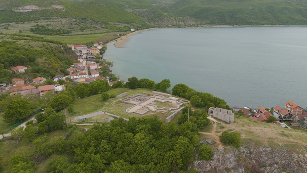 Aerial view of the ancient Lin Basilica ruins on a peninsula overlooking Lake Ohrid surrounded by lush trees and the village of Lin Lin Korce County Albania.