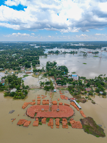 Aerial view of a flooded brick kiln surrounded by submerged rural landscape trees and floodwaters under a cloudy sky in Banshkhali Upazila Chittagong Division Bangladesh. Aerial view of a flooded brick kiln surrounded by submerged rural landscape trees and floodwaters under a cloudy sky in Banshkhali Upazila Chittagong Division Bangladesh.