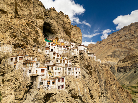 Aerial view of Phukthal Gompa a historic Buddhist monastery built into a cliffside featuring white washed buildings and traditional architecture in Phukthal Ladakh India.