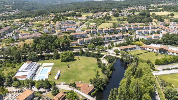 Aerial view of the town of Allariz featuring a river winding through green fields a swimming pool and residential buildings in Allariz Province of Ourense Spain. Aerial view of the town of Allariz featuring a river winding through green fields a swimming pool and residential buildings in Allariz Province of Ourense Spain.