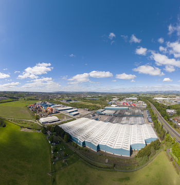 04 May 2026 Aerial view of a large industrial warehouse complex with white roofs surrounded by green fields and a highway under a blue sky with clouds. 04 May 2026 Aerial view of a large industrial warehouse complex with white roofs surrounded by green fields and a highway under a blue sky with clouds.