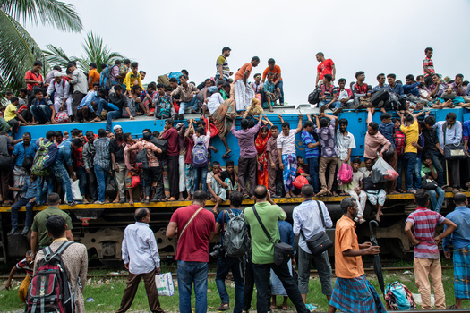 Dhaka Bangladesh 15 June 2018 View of Airport Railway Station with a blue train overcrowded with passengers sitting on the roof and hanging from the sides in the busy city. Dhaka Bangladesh 15 June 2018 View of Airport Railway Station with a blue train overcrowded with passengers sitting on the roof and hanging from the sides in the busy city.