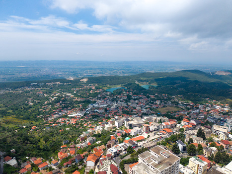 Aerial view of the town of Kruje featuring traditional red roofed houses and green hills under a blue sky with clouds Kruje Durres County Albania.