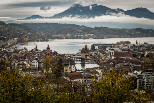 View of the historic old town with the Chapel Bridge and Jesuit Church along the Reuss River and Mount Pilatus under a cloudy sky Lucerne Lucerne Switzerland. View of the historic old town with the Chapel Bridge and Jesuit Church along the Reuss River and Mount Pilatus under a cloudy sky Lucerne Lucerne Switzerland.