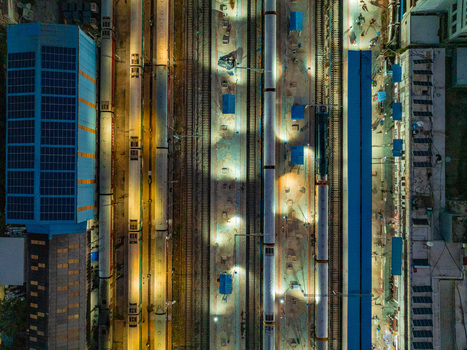 Aerial view of a railway station at night with trains parked on tracks illuminated platforms and solar panels on the roof in Udaipur Rajasthan India. Aerial view of a railway station at night with trains parked on tracks illuminated platforms and solar panels on the roof in Udaipur Rajasthan India.