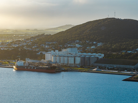 Aerial view of the grain terminal with large silos and a cargo ship docked at the pier situated along the coastline of Vancouver Peninsula Western Australia Australia. Aerial view of the grain terminal with large silos and a cargo ship docked at the pier situated along the coastline of Vancouver Peninsula Western Australia Australia.