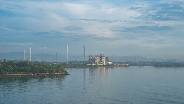 View of the Cebu Port Authority area featuring an unfinished concrete building structure along the coastline with lush greenery under a cloudy sky in Cebu City Central Visayas Philippines. View of the Cebu Port Authority area featuring an unfinished concrete building structure along the coastline with lush greenery under a cloudy sky in Cebu City Central Visayas Philippines.