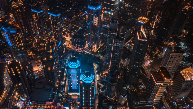 Aerial view of illuminated skyscrapers and glowing office buildings in the dense urban skyline of Jakarta Indonesia.