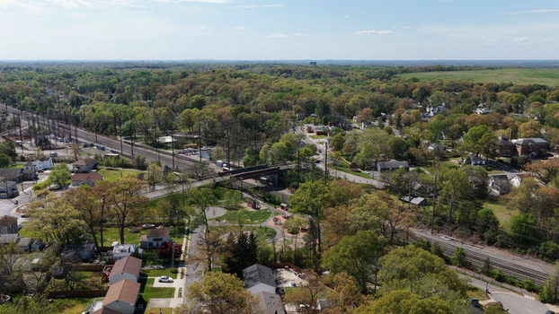 Aerial view of the suburban landscape featuring a railway line crossing a bridge residential houses and a small park with playground equipment in Bowie Maryland United States.