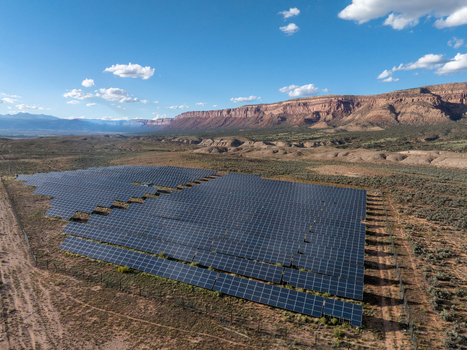 Aerial view of a large solar farm with rows of photovoltaic panels situated in a desert landscape with mesas in the background in Colorado United States. Aerial view of a large solar farm with rows of photovoltaic panels situated in a desert landscape with mesas in the background in Colorado United States.