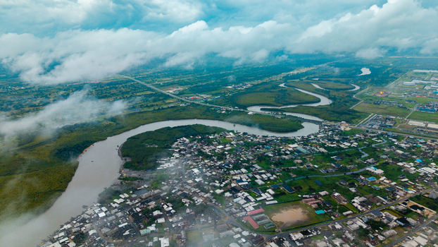 Aerial view of the winding Kwa Ibo River flowing past residential areas and lush greenery under a cloudy sky in Kwa Ibo Akwa Ibom Nigeria.