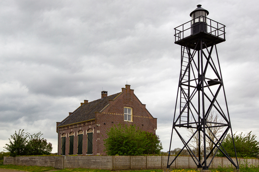 View of the historic Schokland lighthouse tower and the former church building under a cloudy sky in Schokland Flevoland Netherlands.