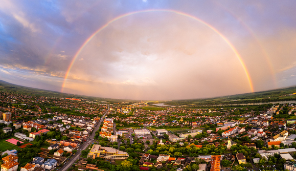 Aerial view of a vibrant double rainbow arching over the urban landscape and residential rooftops at sunset Sremska Mitrovica Serbia.